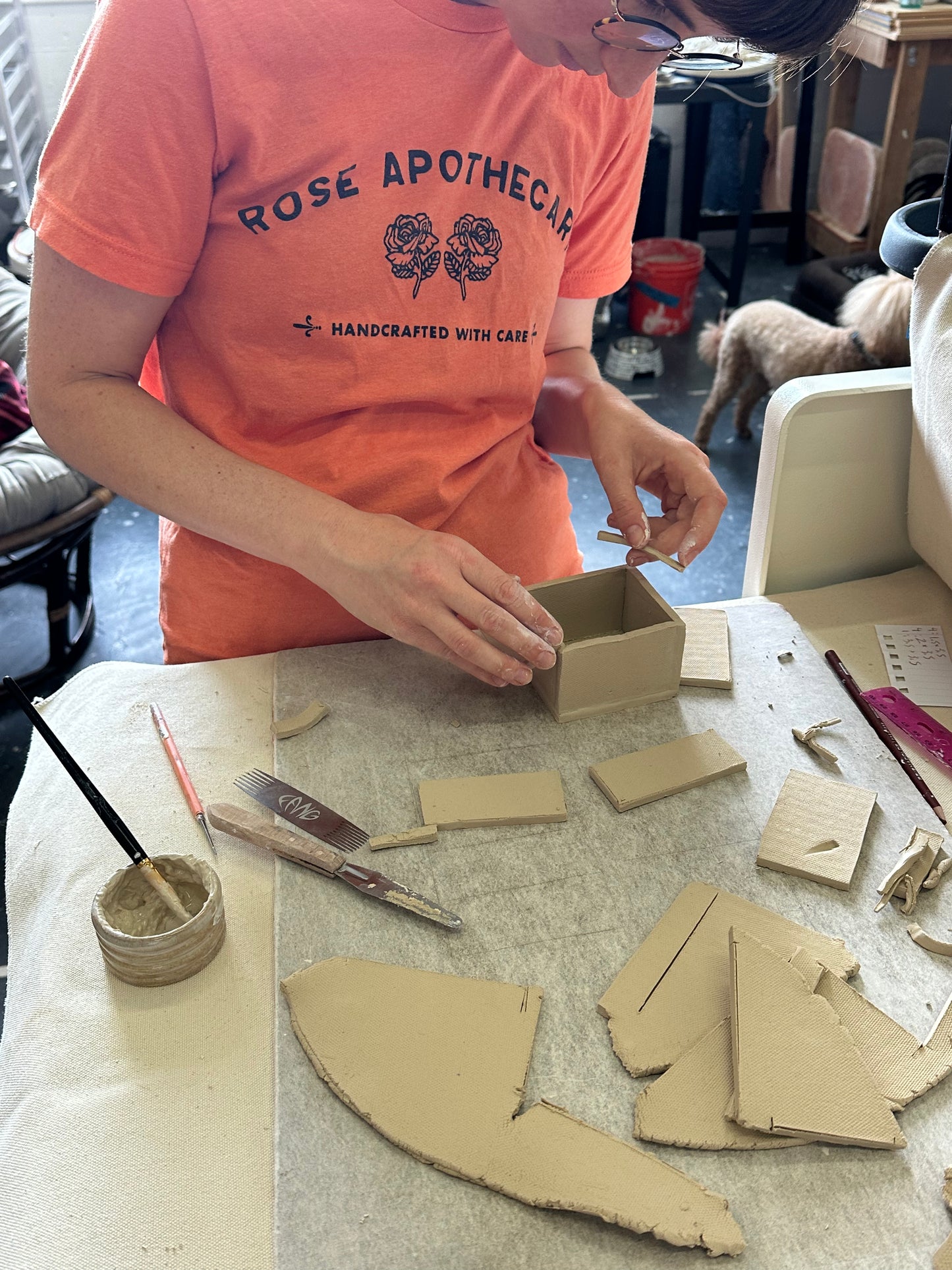 Person working with clay on a table in a workshop setting