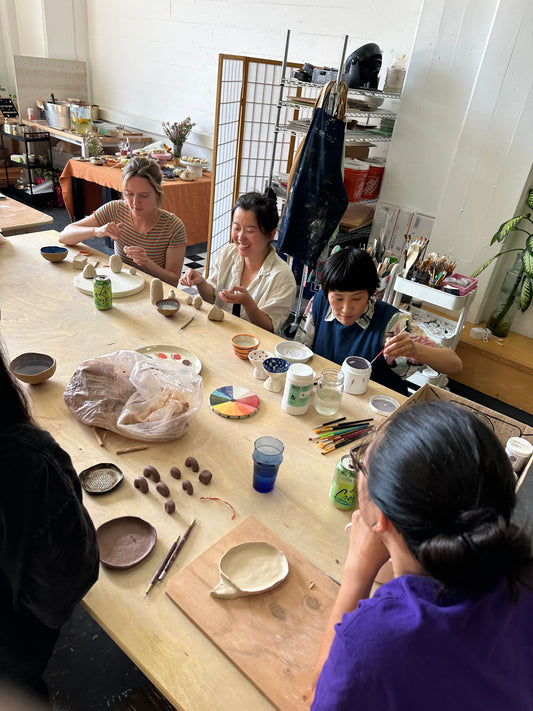 Group of people working on pottery in a studio setting