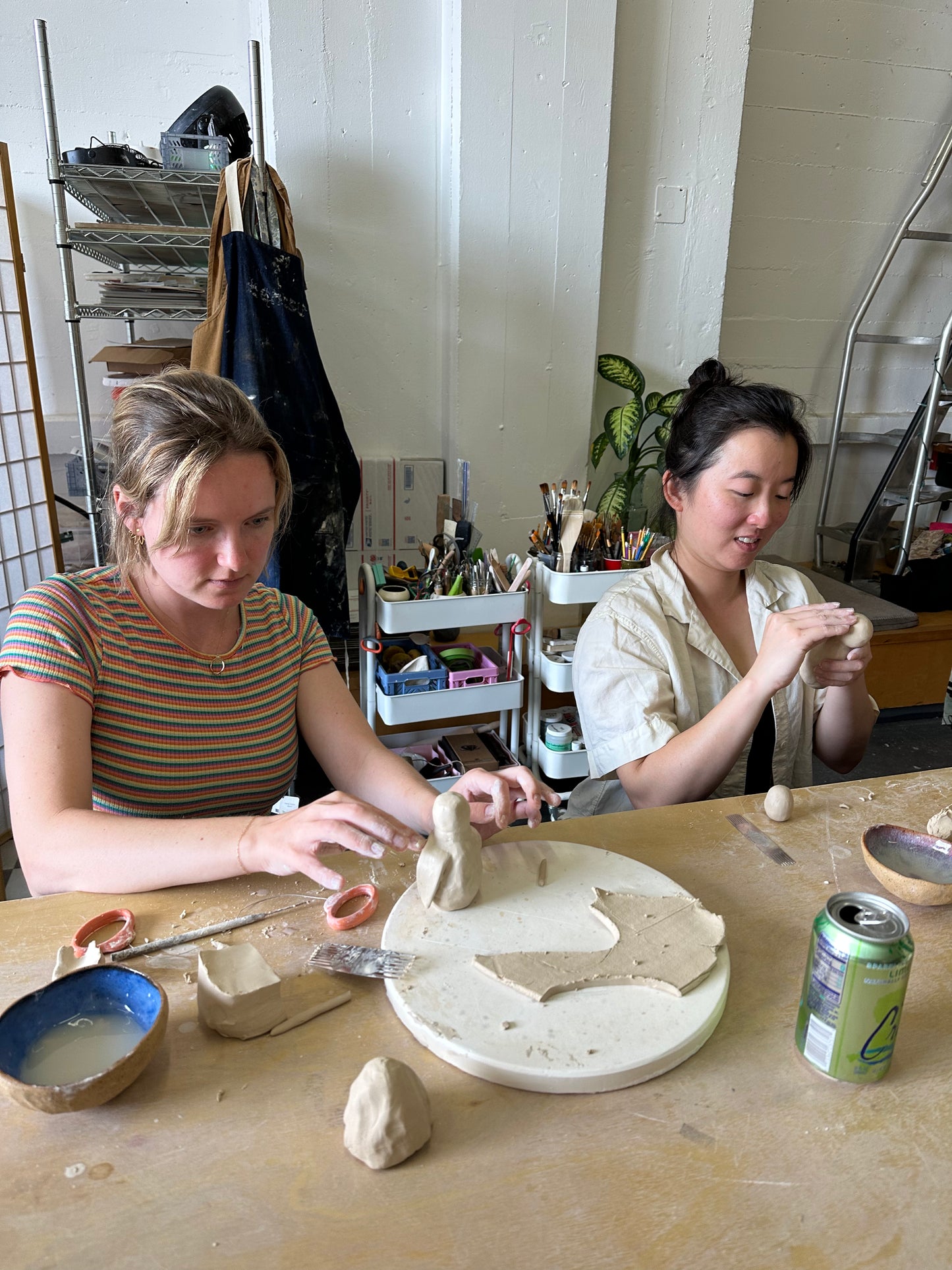 Two women working with clay in a pottery studio.