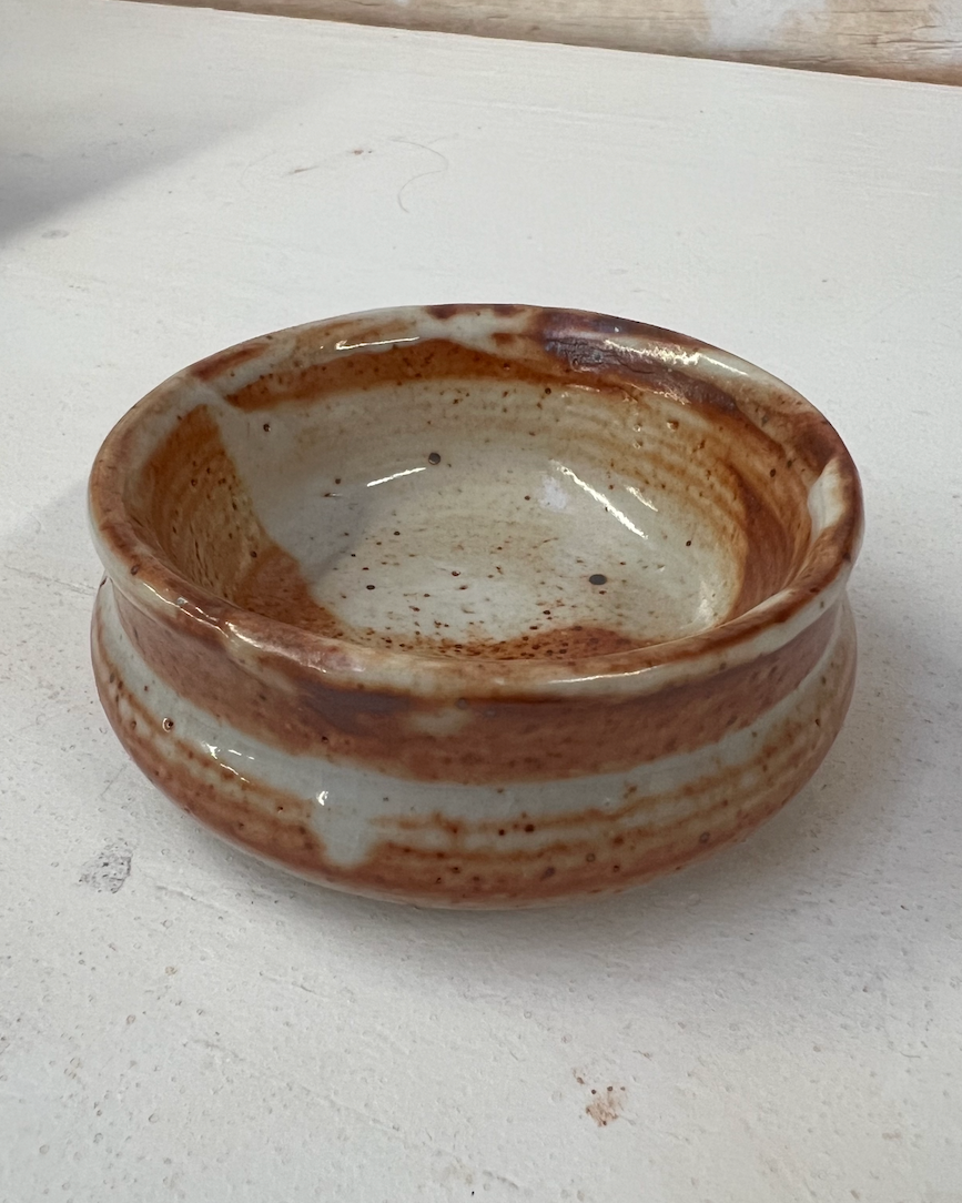 Ceramic bowl with brown and white speckled glaze on a white surface